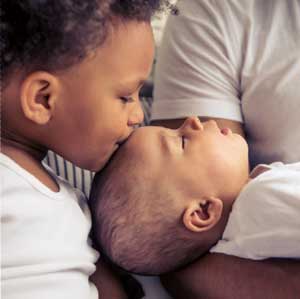 Sibling kissing new born on forehead